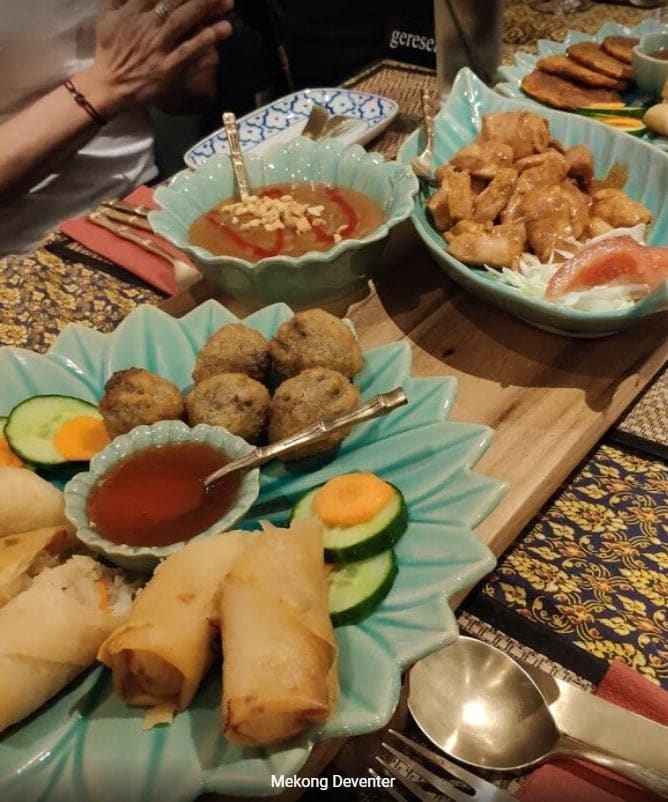 Voorgerechten op tafel: loempia`s, viskoekjes, satésaus en kip met zoetzure groente.