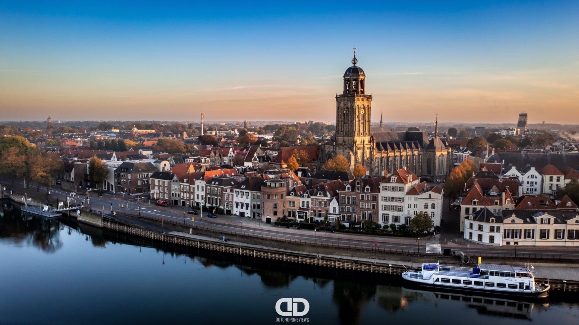 Deventer aan de IJssel bij zonsopkomst, met de toren van de Lebuinuskerk boven de kades.