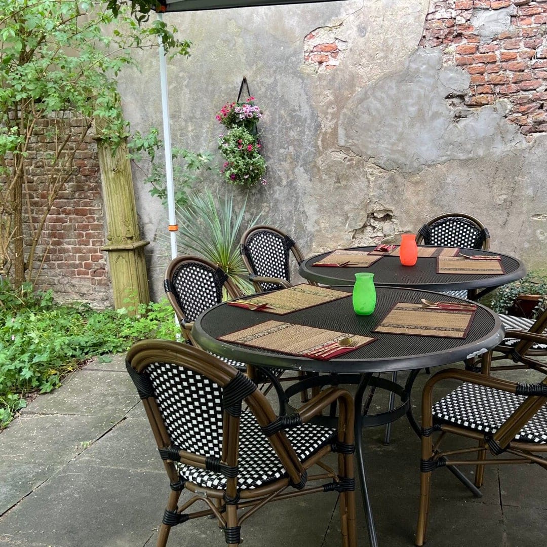 Terrastafels voor de oude pleisterwand met hangende bloemen in de binnentuin.