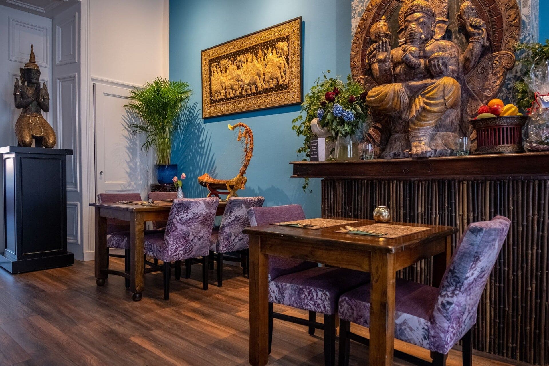 Eetzaal van Mekong Deventer met een gouden Ganeshabeeld, een blauwe wand en gedekte tafels.