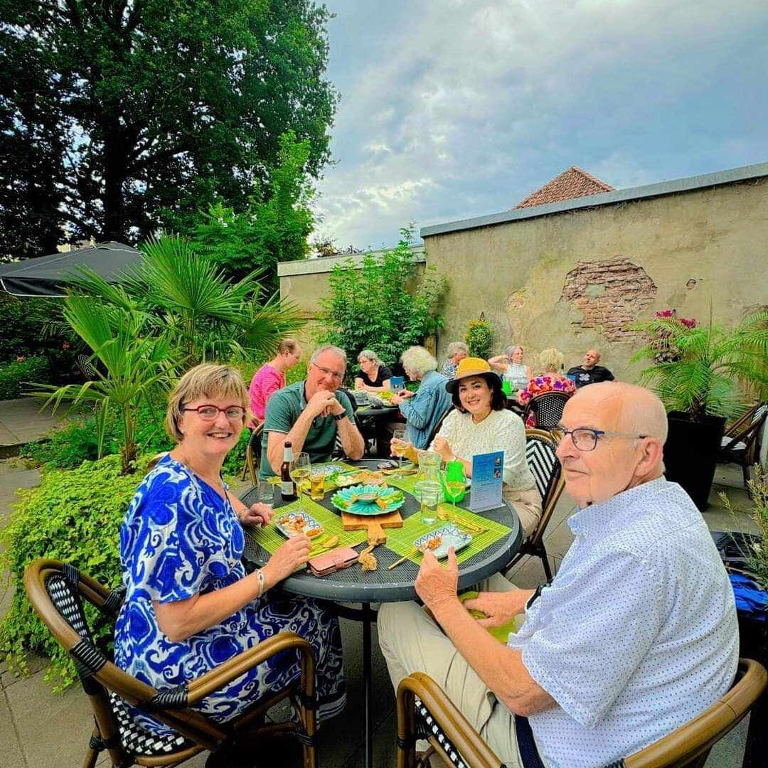 Gasten aan een terrastafel in de binnentuin op een zomeravond.